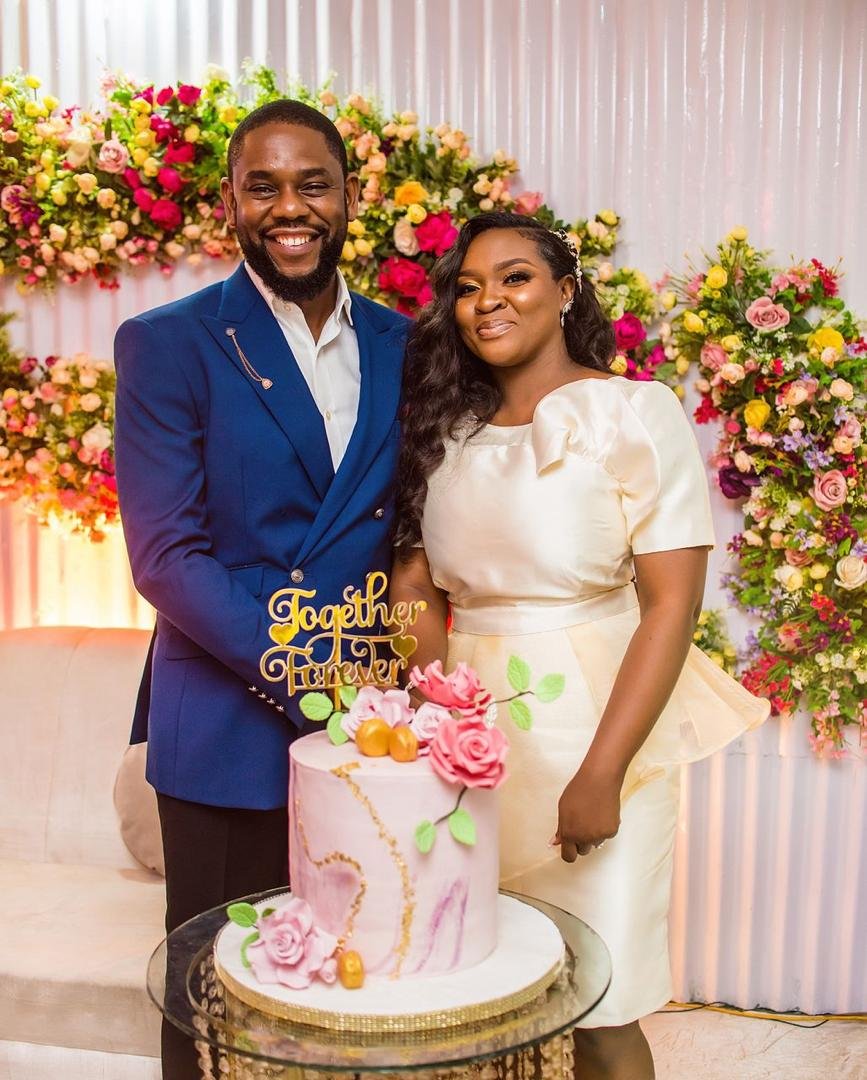 Couple smiling next to wedding cake